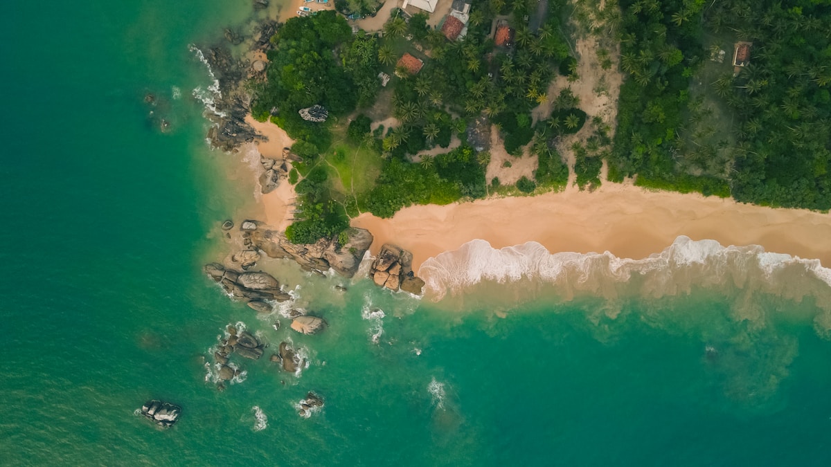 Aerial view of a tropical beach and forested coastline on the east coast of Sri Lanka