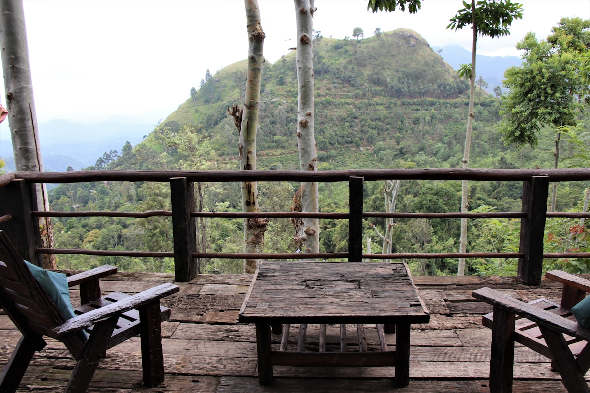 Rustic resort patio with wooden table and chairs overlooking Ella mountain valley, Sri Lanka