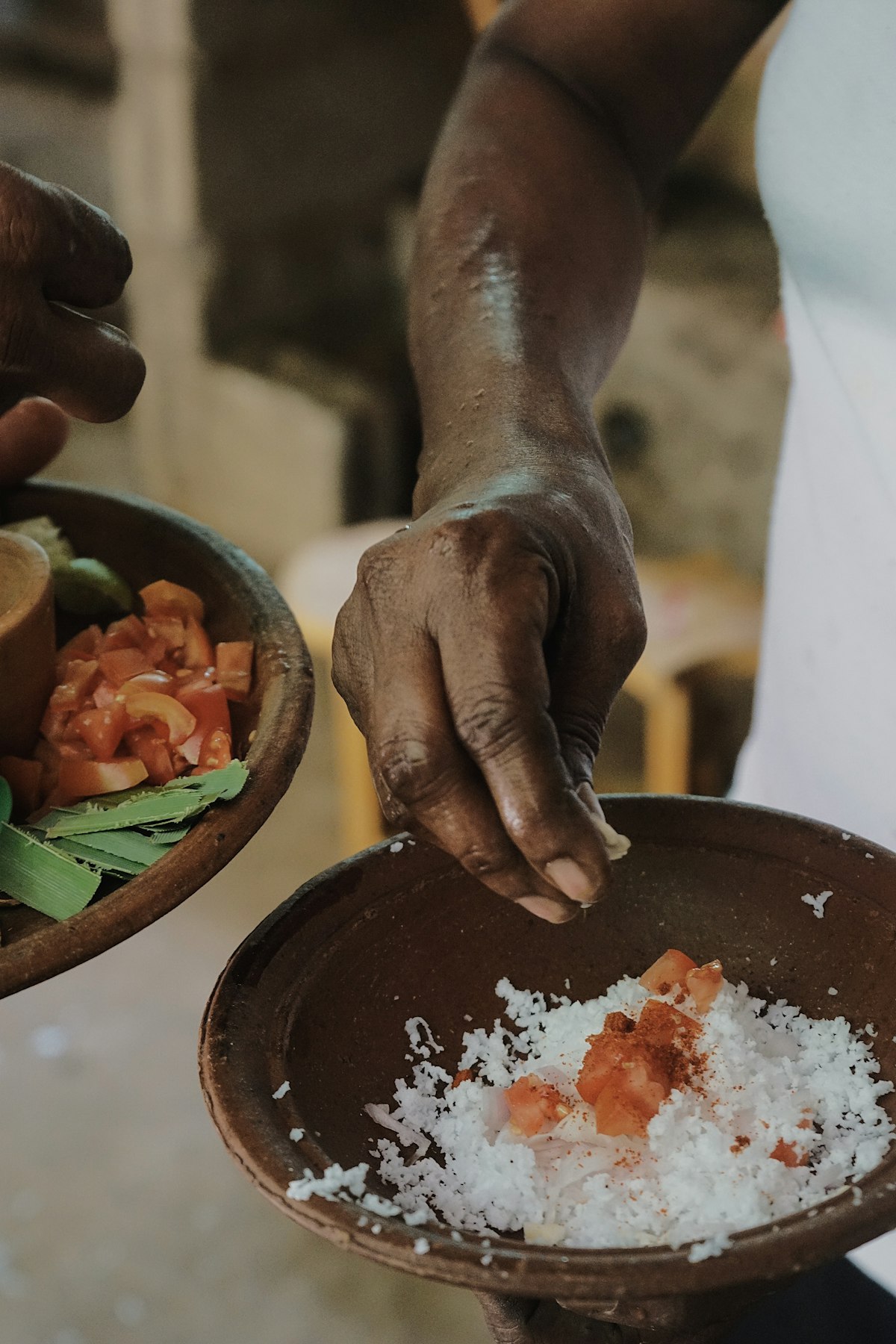 Hands preparing spiced coconut in a clay bowl during a Sri Lanka cooking class in Kandy