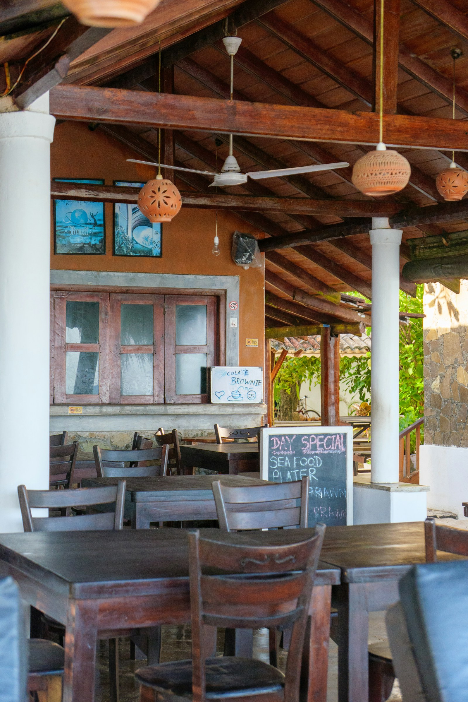 Open-air restaurant with wooden tables and ceiling fans in Sri Lanka hill country