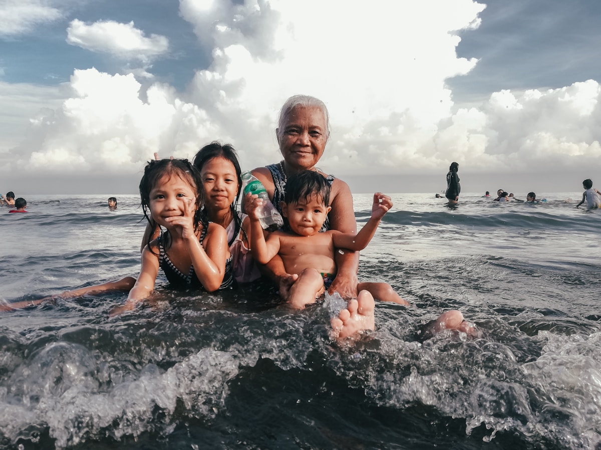 Family with children playing in tropical ocean waves, Sri Lanka