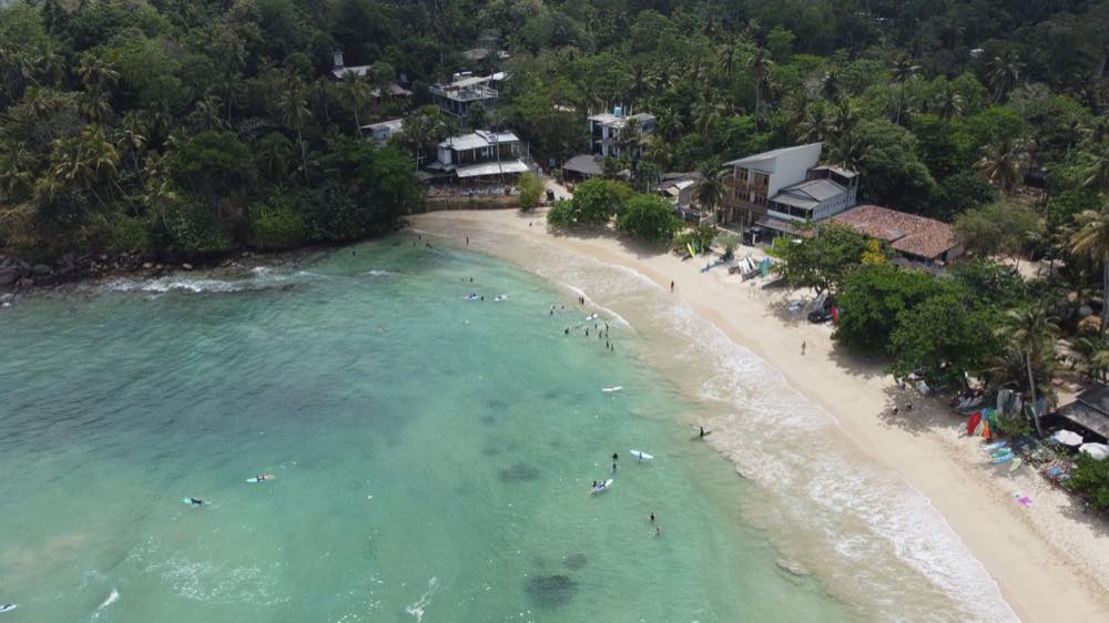 Türkisfarbene Bucht und Surfer in Hiriketiya an der Südküste