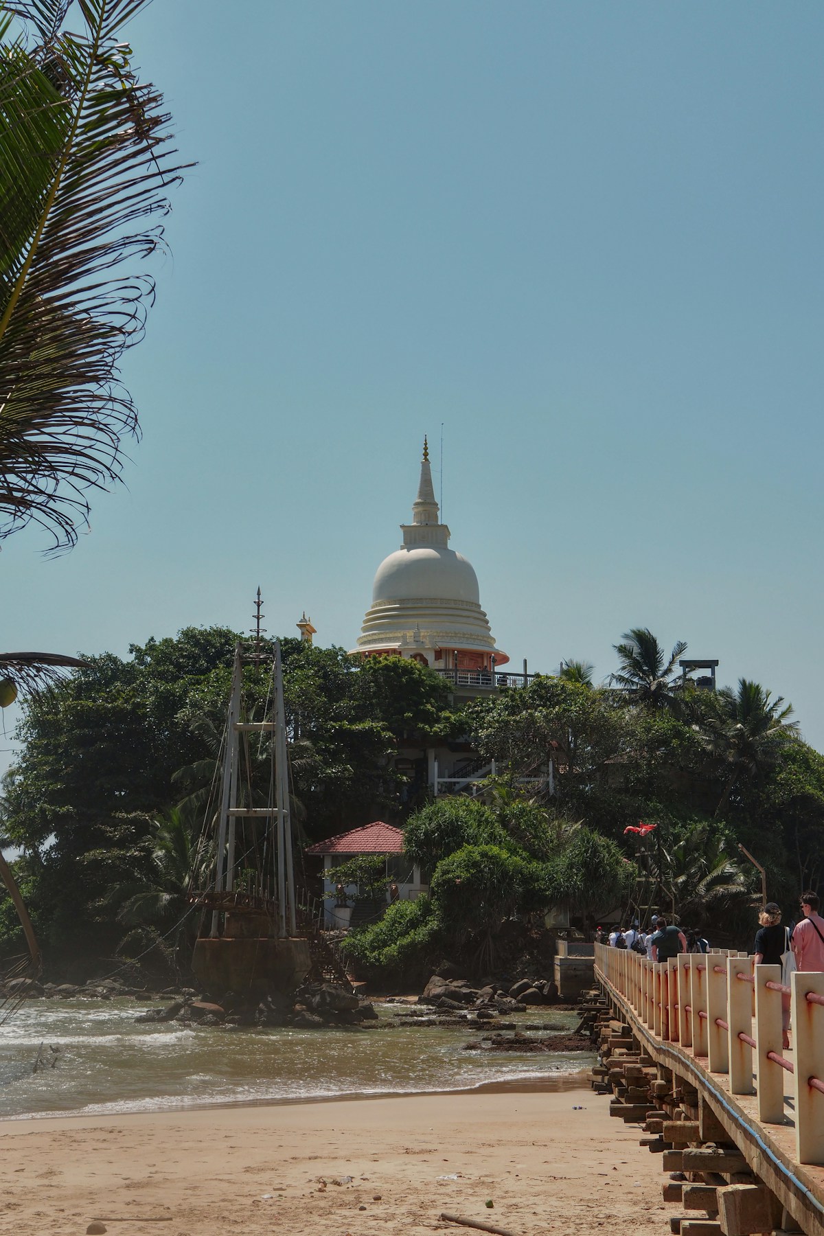 White Buddhist stupa on a lush green island with a wooden footbridge, northern Sri Lanka