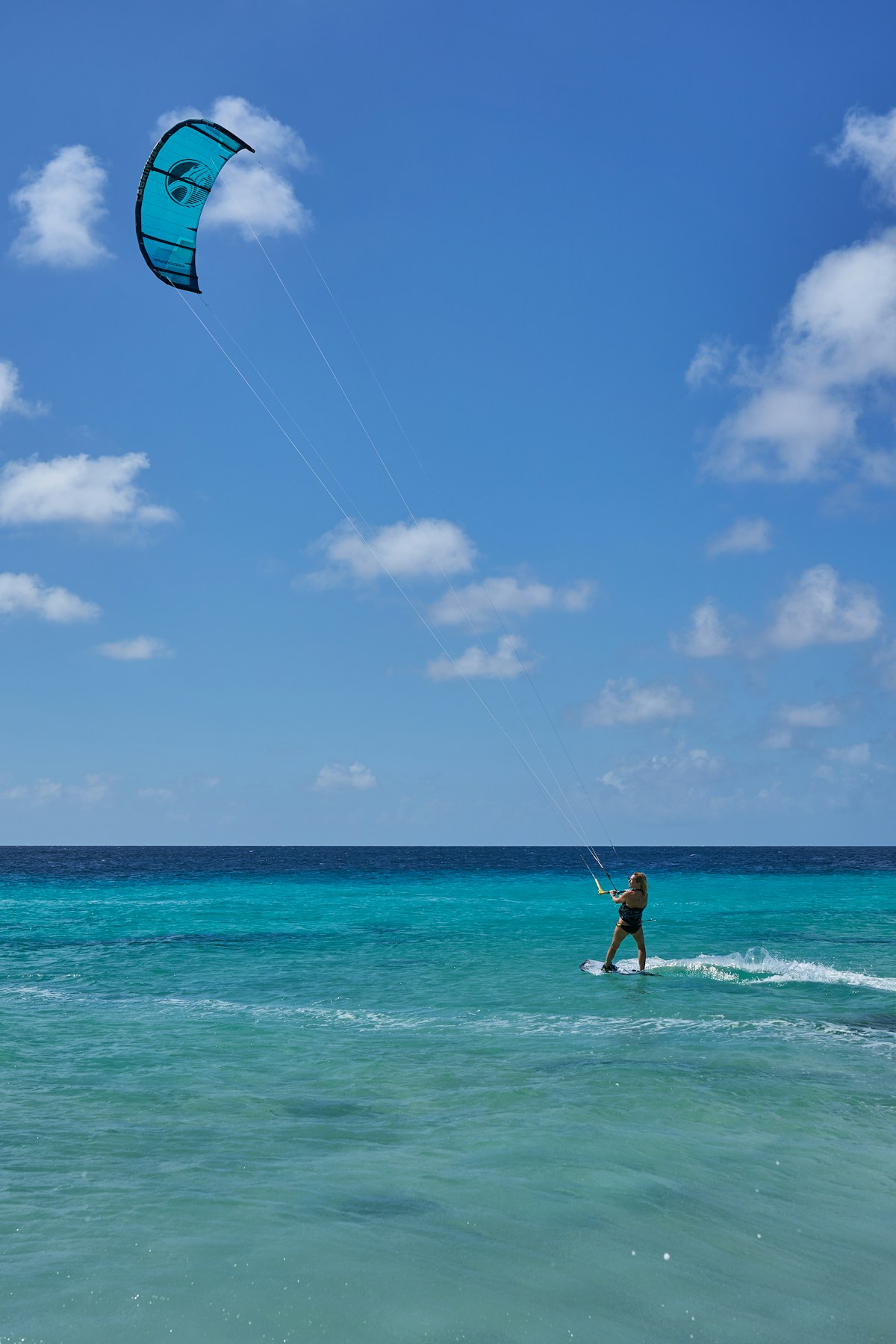 Woman kitesurfing on turquoise water under a clear blue sky