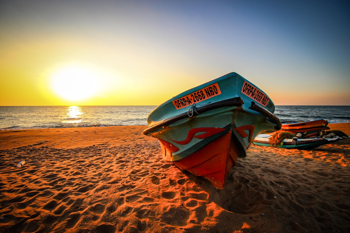Red and blue fishing boat on the beach at sunset, Negombo, Sri Lanka