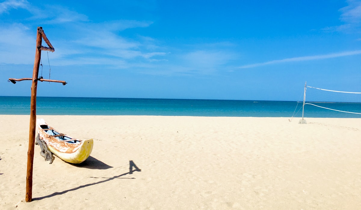 Wide white sand beach with traditional wooden boat, Pasikuda Bay, eastern Sri Lanka