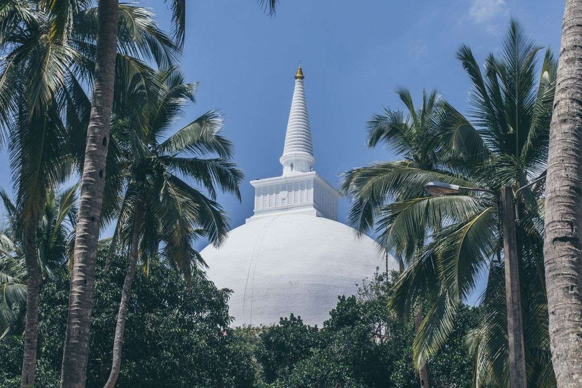 White stupa at Mihintale rising above coconut palms in Sri Lanka