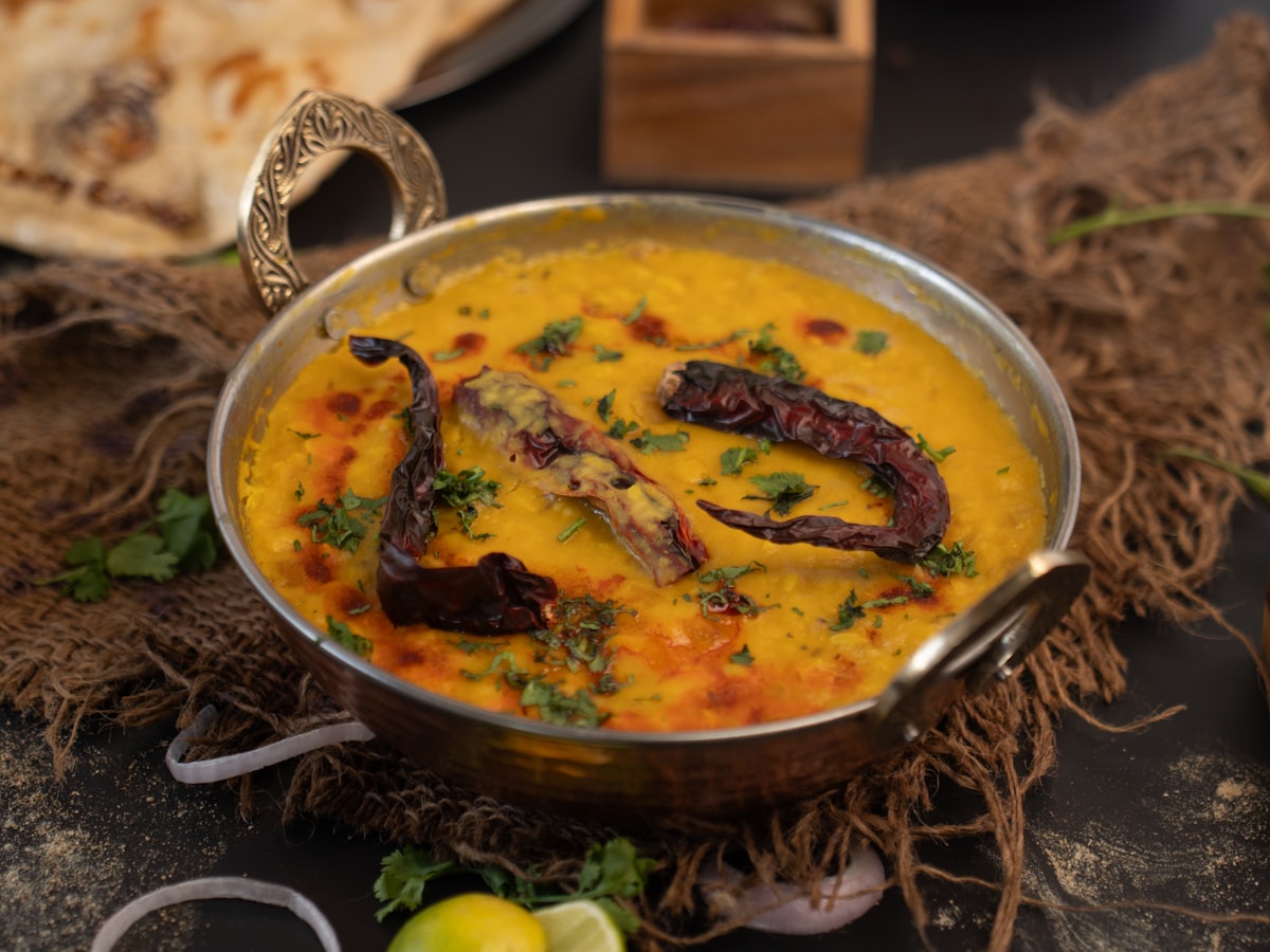 Golden dhal curry in a copper kadai with dried chillies and coriander garnish