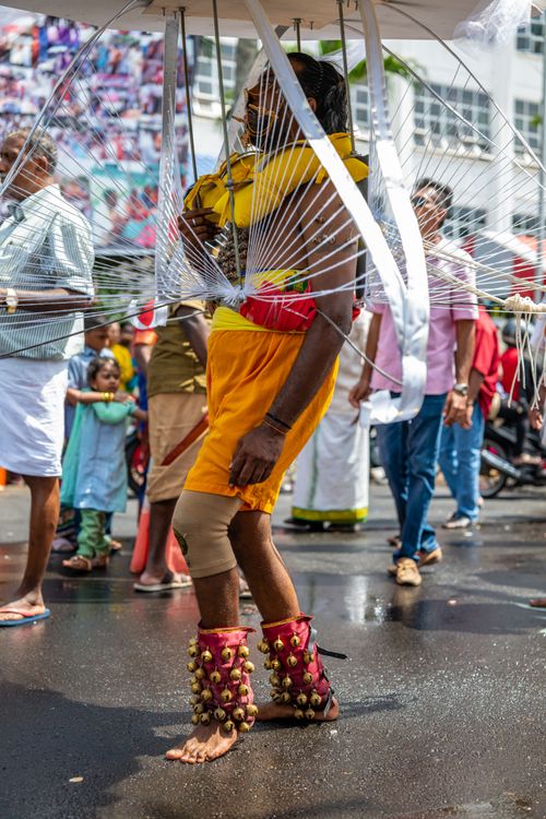 Kavadi dancer carrying a vel kavadi frame through the streets during a Tamil Hindu procession